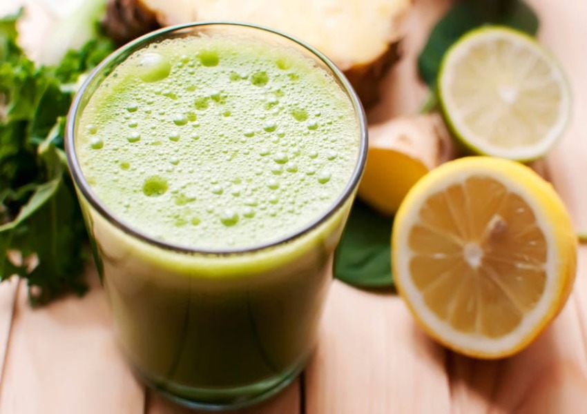 A glass of green juice with lemon and other fruits.