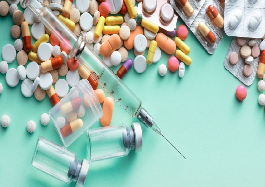 A table topped with lots of pills and syringes.