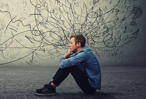 A man sitting on the ground with his head in his hands.