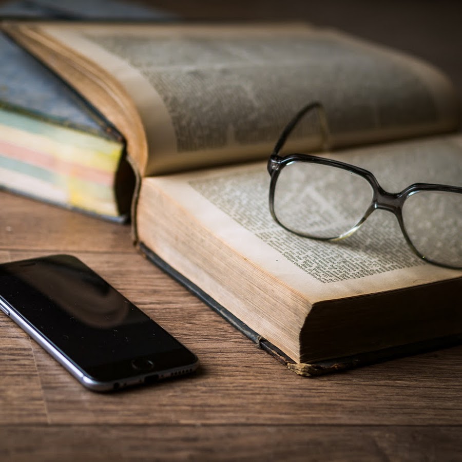 A cell phone and some books on the table