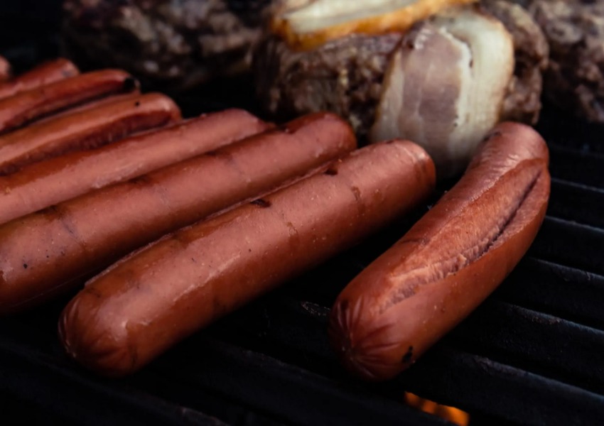 A grill with hot dogs and other food on it.